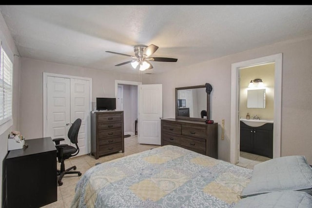 bedroom with a sink, a ceiling fan, light tile patterned floors, ensuite bathroom, and a closet