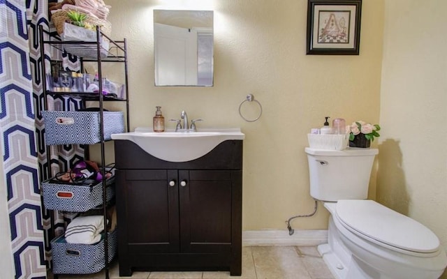 half bath with vanity, baseboards, toilet, and tile patterned flooring