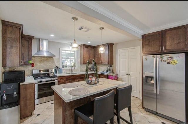 kitchen with decorative backsplash, wall chimney exhaust hood, a sink, appliances with stainless steel finishes, and light tile patterned floors