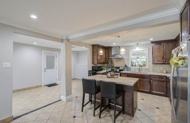 kitchen featuring appliances with stainless steel finishes, tasteful backsplash, a center island, a sink, and wall chimney exhaust hood