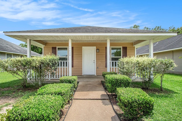 view of front of house with a porch, a shingled roof, and a front yard