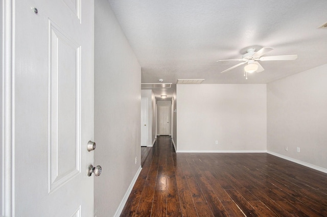 spare room featuring baseboards, ceiling fan, dark wood finished floors, and visible vents