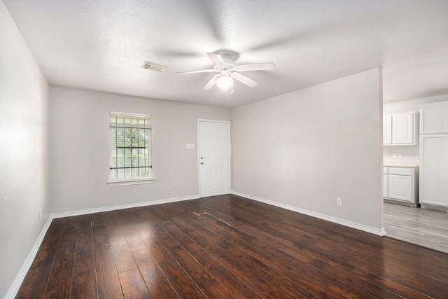 spare room with visible vents, dark wood-style flooring, ceiling fan, and baseboards