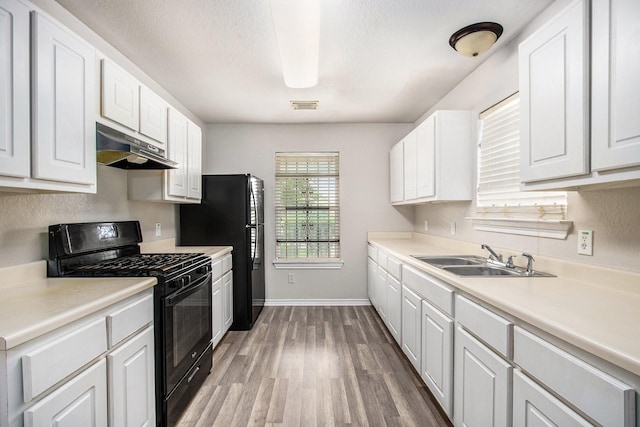 kitchen with under cabinet range hood, white cabinetry, a sink, and black appliances