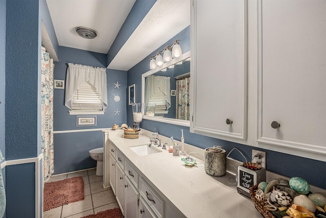 bathroom with vanity, tile patterned flooring, baseboards, and toilet