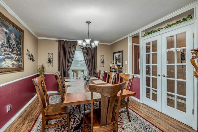 dining room featuring ornamental molding, french doors, wood finished floors, and a notable chandelier