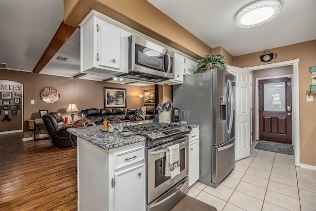 kitchen featuring appliances with stainless steel finishes, white cabinetry, open floor plan, a peninsula, and visible vents