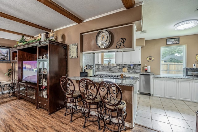 kitchen with plenty of natural light, decorative backsplash, a textured ceiling, and white cabinetry