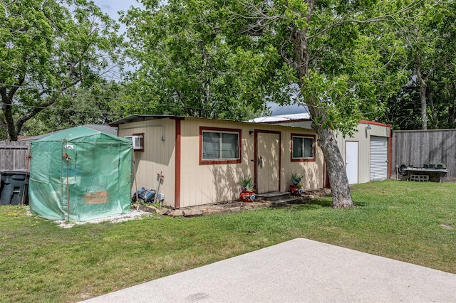 exterior space featuring an outdoor structure, fence, a front yard, a patio, and metal roof
