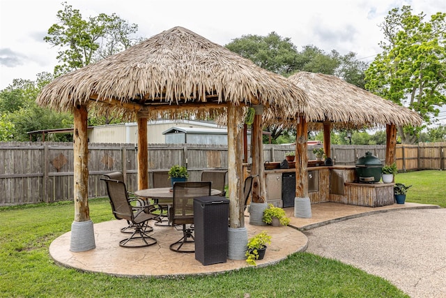 view of patio featuring an outdoor kitchen, grilling area, a gazebo, and a fenced backyard