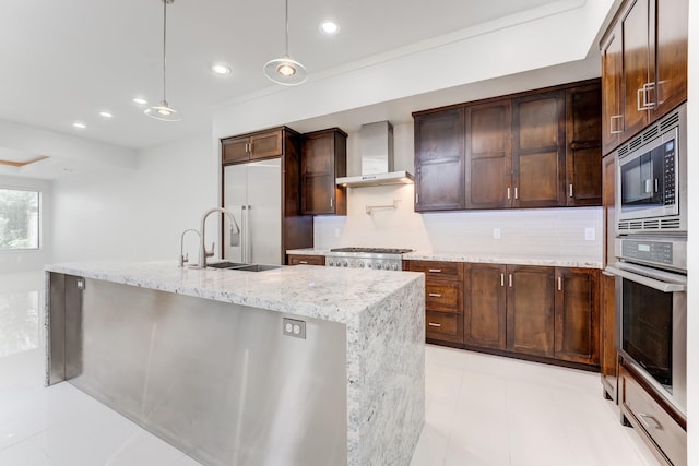 kitchen with built in appliances, dark brown cabinetry, wall chimney range hood, recessed lighting, and backsplash