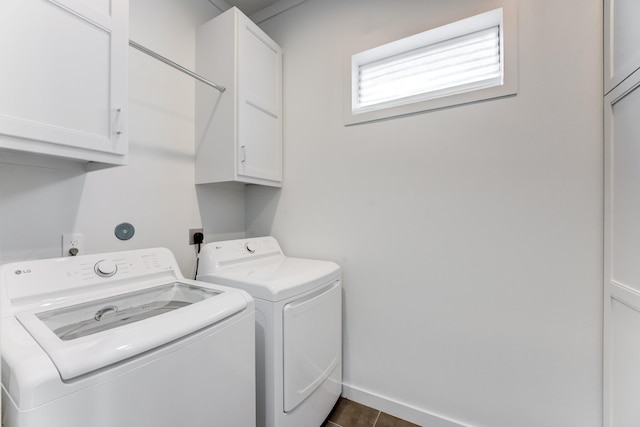 washroom featuring dark tile patterned flooring, baseboards, cabinet space, and washing machine and clothes dryer