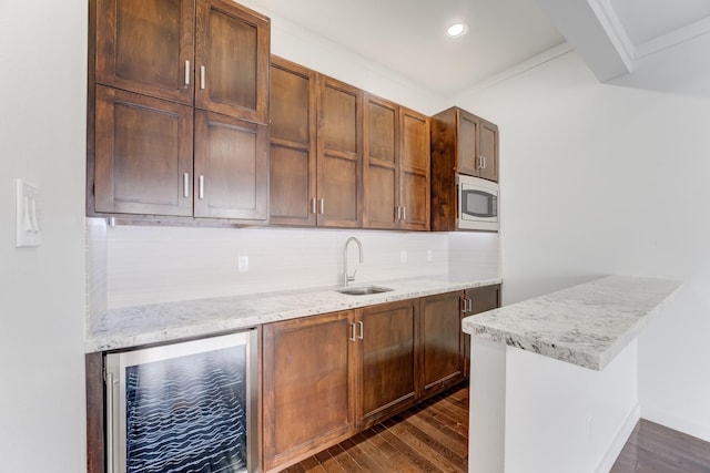 kitchen with decorative backsplash, dark wood finished floors, a sink, white microwave, and beverage cooler