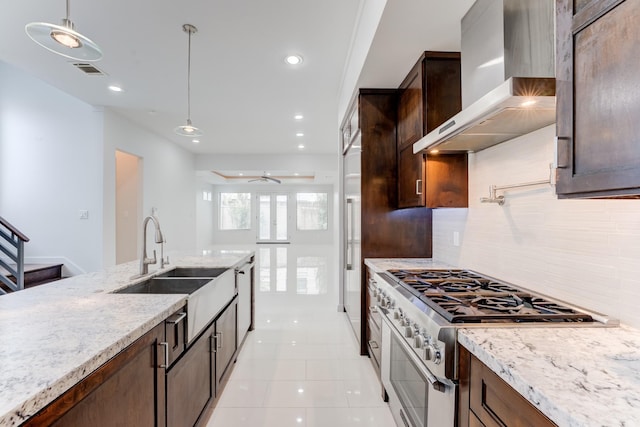 kitchen with visible vents, ceiling fan, wall chimney range hood, a sink, and high end range