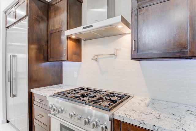 kitchen featuring light stone countertops, dark brown cabinets, extractor fan, and high quality appliances