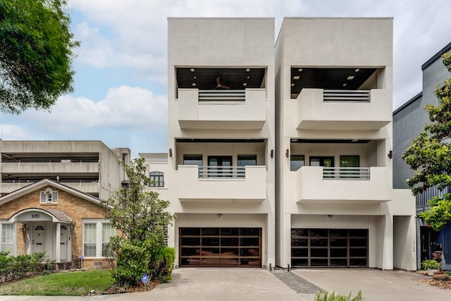 view of front of home with an attached garage, driveway, stucco siding, and a balcony