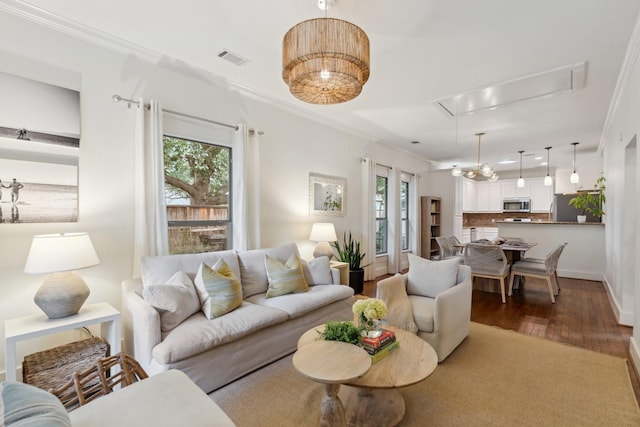 living room featuring attic access, wood finished floors, a wealth of natural light, and ornamental molding