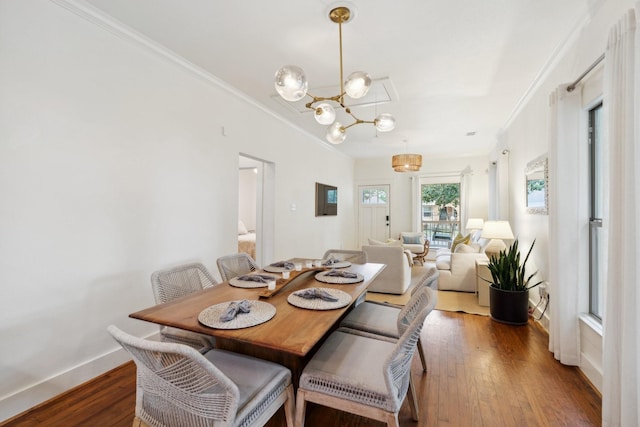 dining room featuring baseboards, ornamental molding, wood finished floors, and an inviting chandelier