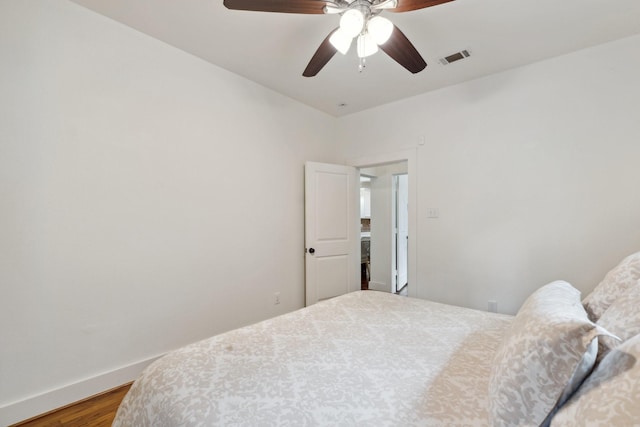 bedroom with baseboards, ceiling fan, wood finished floors, and visible vents