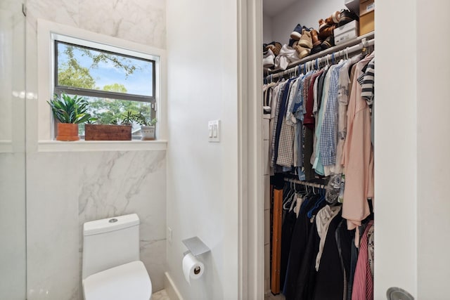 bathroom featuring a spacious closet and toilet