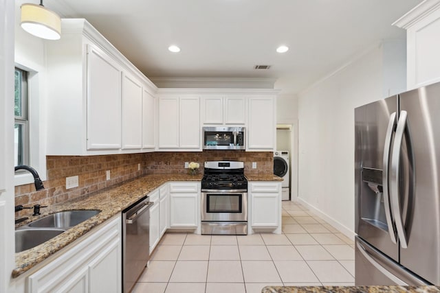kitchen with visible vents, washer / dryer, a sink, backsplash, and stainless steel appliances