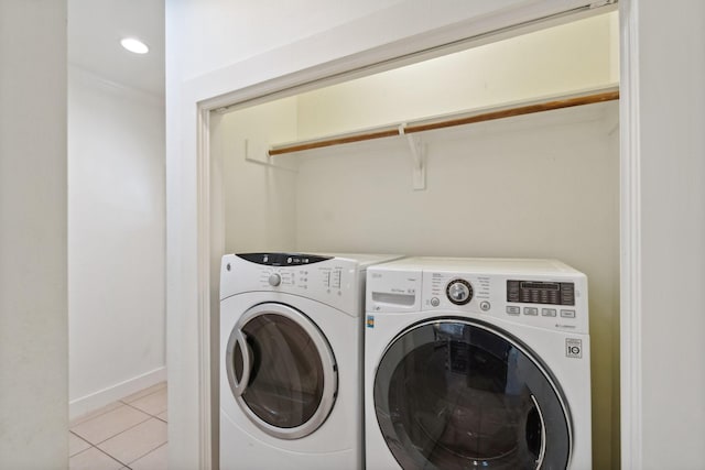 clothes washing area featuring laundry area, baseboards, light tile patterned floors, and washer and dryer