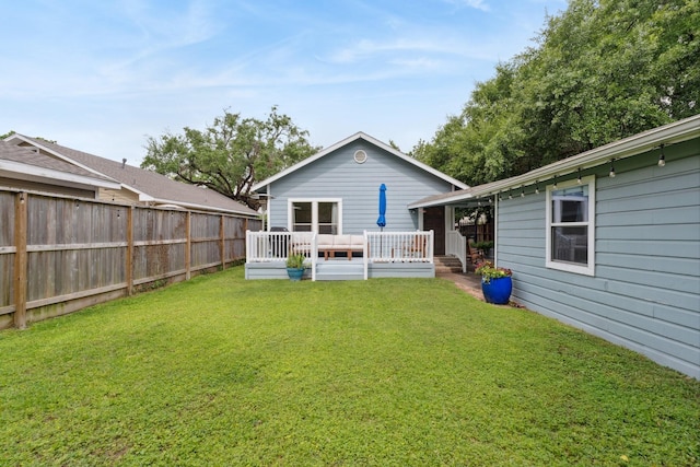 rear view of house featuring fence, a yard, and a deck