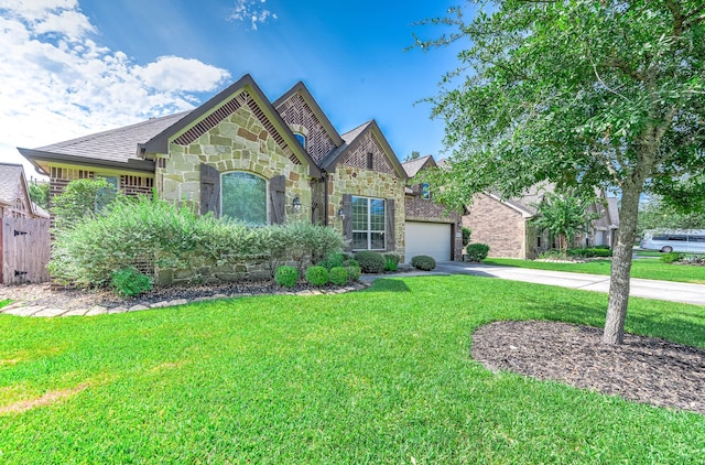 view of front facade featuring fence, stone siding, a garage, a front yard, and concrete driveway