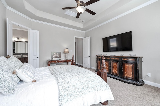 carpeted bedroom with crown molding, baseboards, a raised ceiling, a ceiling fan, and ensuite bath