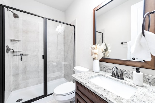 bathroom featuring toilet, a shower stall, and vanity
