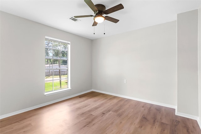 spare room featuring light wood-style floors, baseboards, a ceiling fan, and visible vents