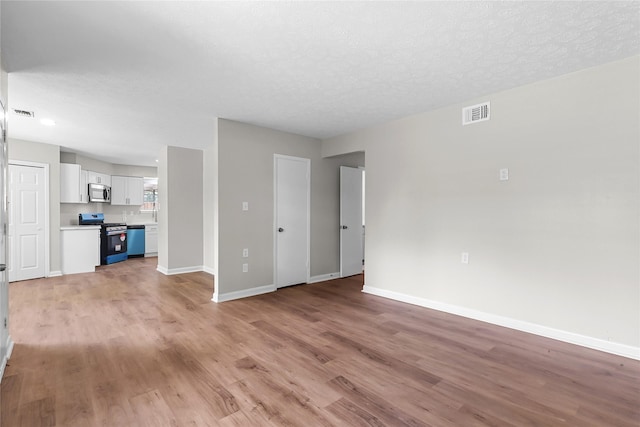 unfurnished living room featuring baseboards, visible vents, and light wood-type flooring