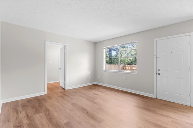 interior space with a textured ceiling, baseboards, and light wood-type flooring