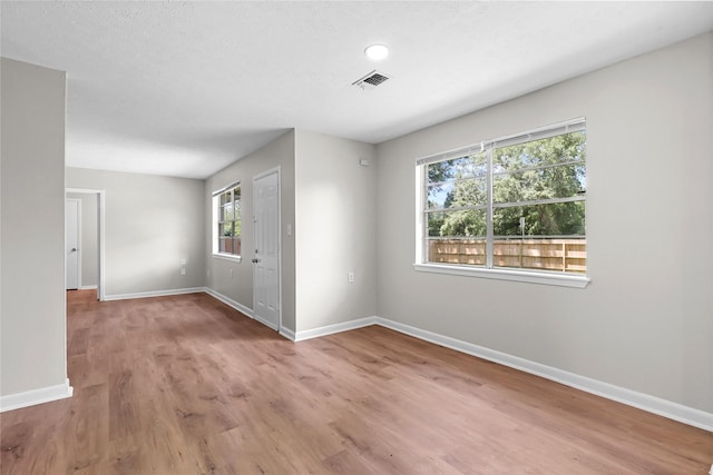 spare room featuring visible vents, baseboards, and wood finished floors