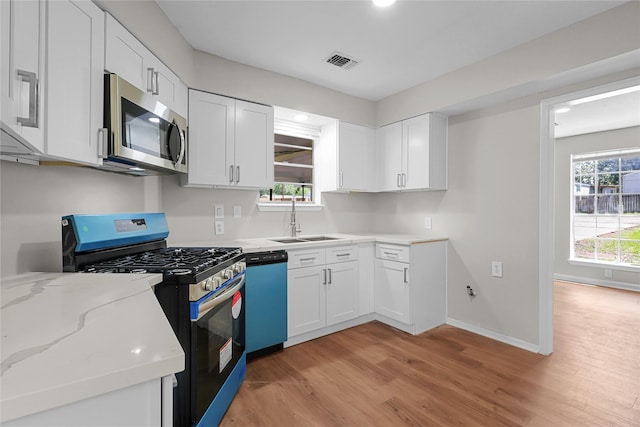 kitchen with visible vents, white cabinetry, a sink, light wood-style flooring, and appliances with stainless steel finishes