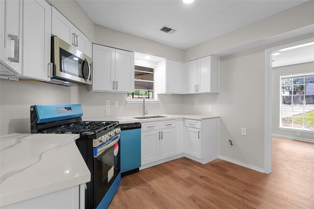 1403 Marilyn St, Conroe, TX 77301 - kitchen with appliances with stainless steel finishes, a sink, light wood finished floors, and white cabinets