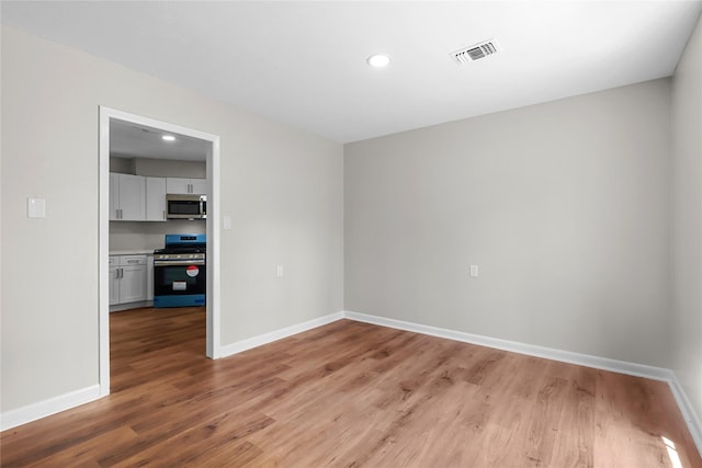 empty room featuring recessed lighting, baseboards, visible vents, and light wood-type flooring