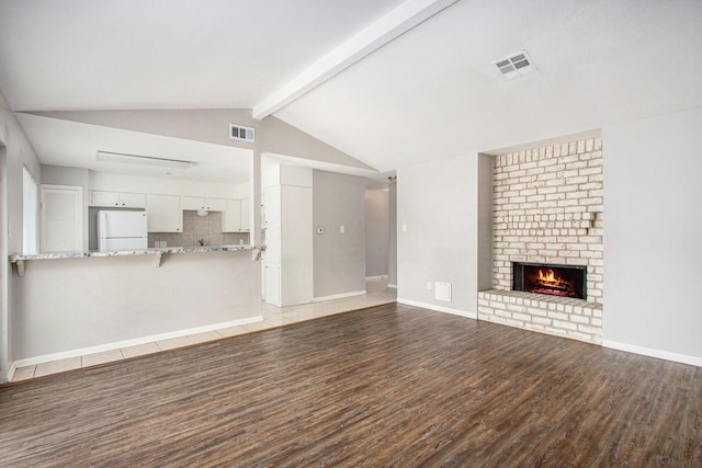 3622 Pine Ridge Ln, Houston, TX 77088 - unfurnished living room with visible vents, lofted ceiling with beams, light wood finished floors, and a brick fireplace