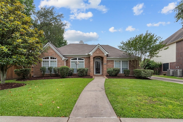 view of front of home featuring brick siding, a front lawn, a shingled roof, and central AC