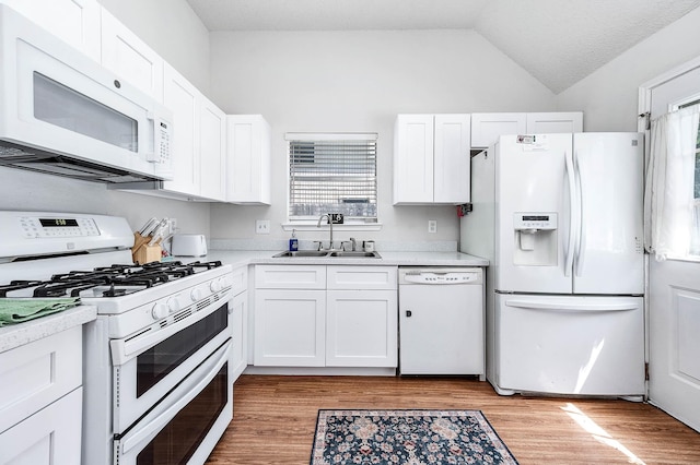 kitchen featuring a sink, white appliances, light countertops, white cabinetry, and lofted ceiling