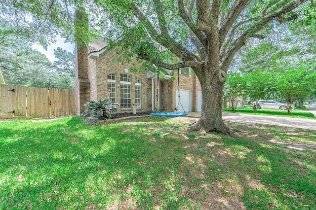 view of yard with fence and concrete driveway