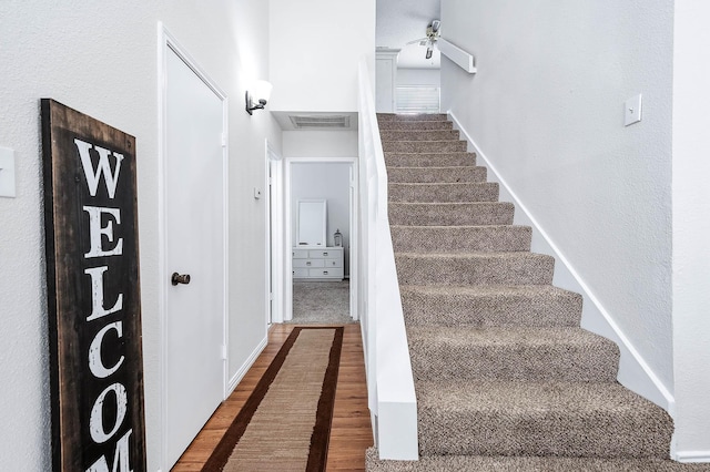 stairway with visible vents, a ceiling fan, baseboards, and wood finished floors