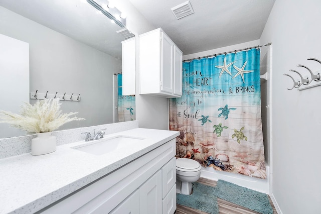 full bathroom with shower / bath combination with curtain, visible vents, wood finished floors, vanity, and toilet
