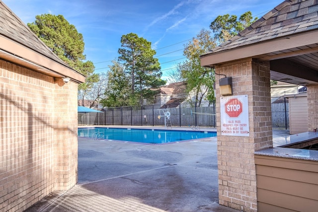 community pool with a patio and fence