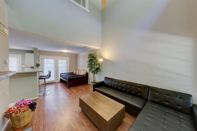 living area featuring baseboards, wood finished floors, and a high ceiling