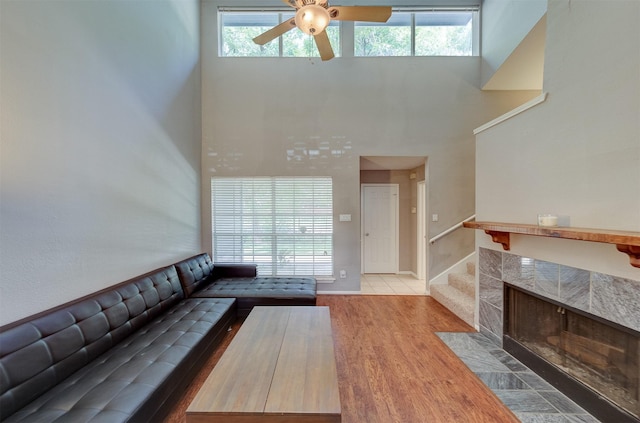 unfurnished living room featuring a ceiling fan, wood finished floors, and a towering ceiling