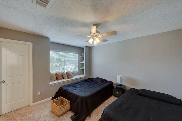 carpeted bedroom featuring ceiling fan, a textured ceiling, and visible vents