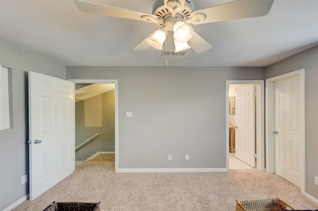 unfurnished bedroom with a textured ceiling, baseboards, light colored carpet, and visible vents