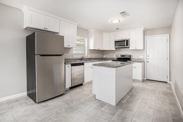kitchen featuring white cabinets, a kitchen island, stainless steel appliances, and visible vents