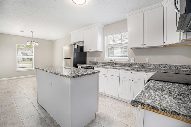 kitchen with a center island, a sink, white cabinets, a chandelier, and stainless steel appliances
